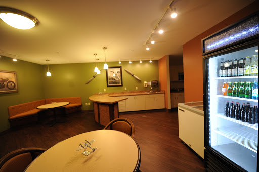 A modern kitchen and dining area featuring green walls, stylish lighting, and minimalistic furniture.