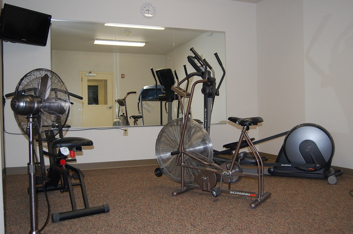 A small gym with various exercise equipment including stationary bikes and an elliptical machine.