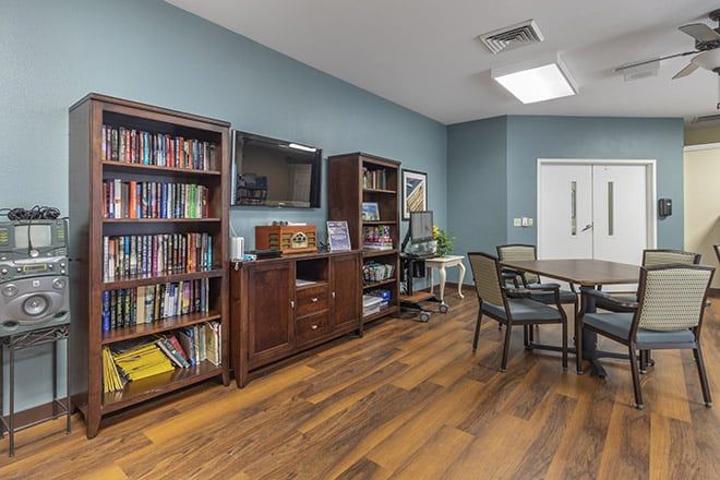 A cozy reading area featuring bookshelves, a table, and chairs on a wooden floor.