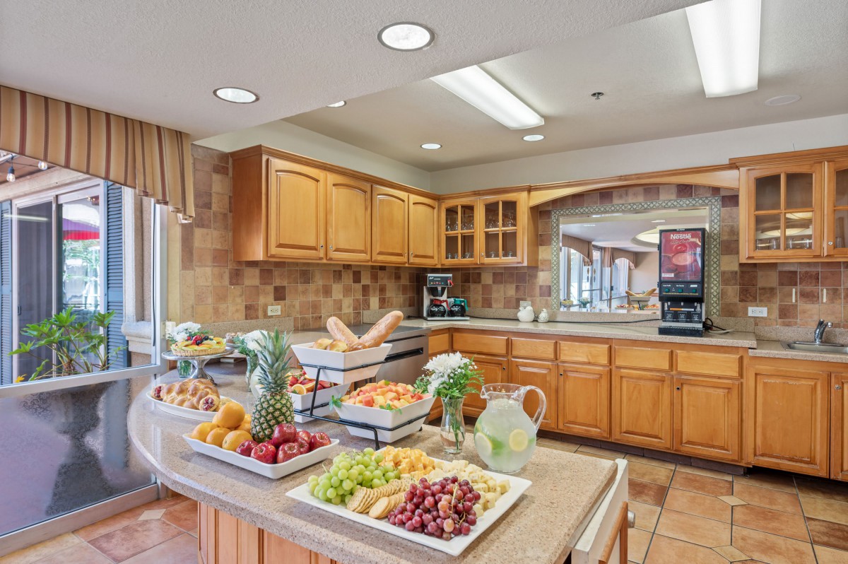 A well-organized kitchen featuring a breakfast buffet with a variety of fresh fruits on the countertop.