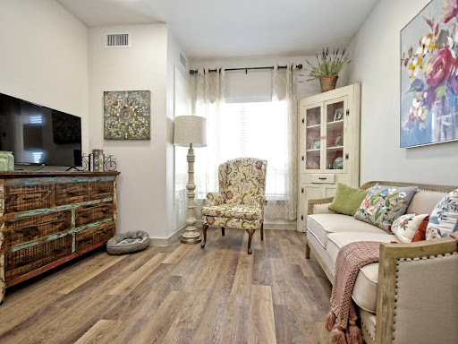 A cozy living room featuring an elegant armchair, a television, and warm wooden flooring.