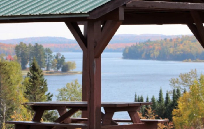 A scenic view of a lake surrounded by trees, framed by a wooden structure.