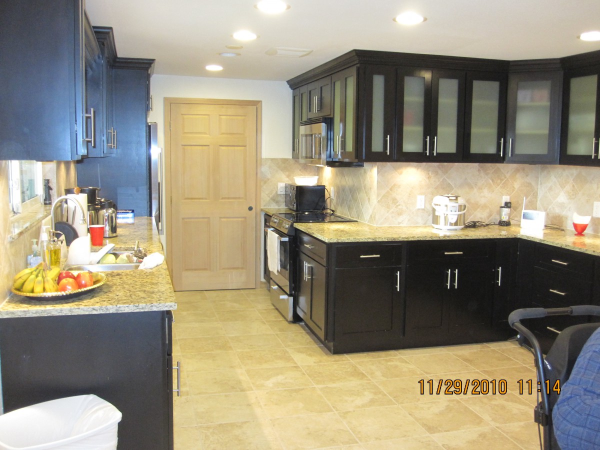 A modern kitchen with dark cabinets and tiled flooring.