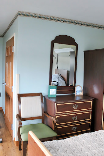 A cozy bedroom corner featuring a wooden vanity with a mirror, accompanied by an elegant chair.