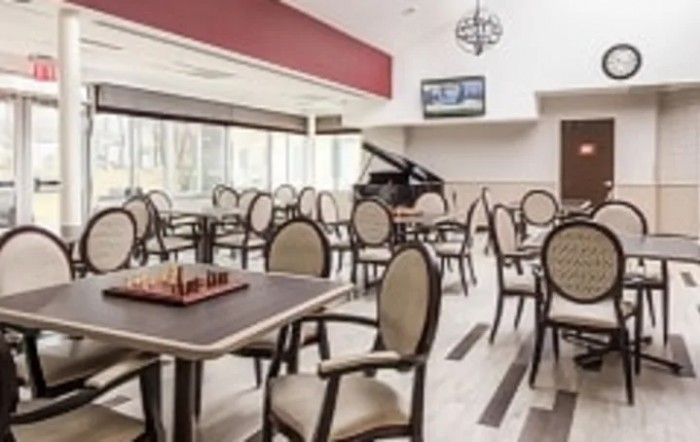A modern dining room with empty chairs and tables, featuring a chess board and a piano.