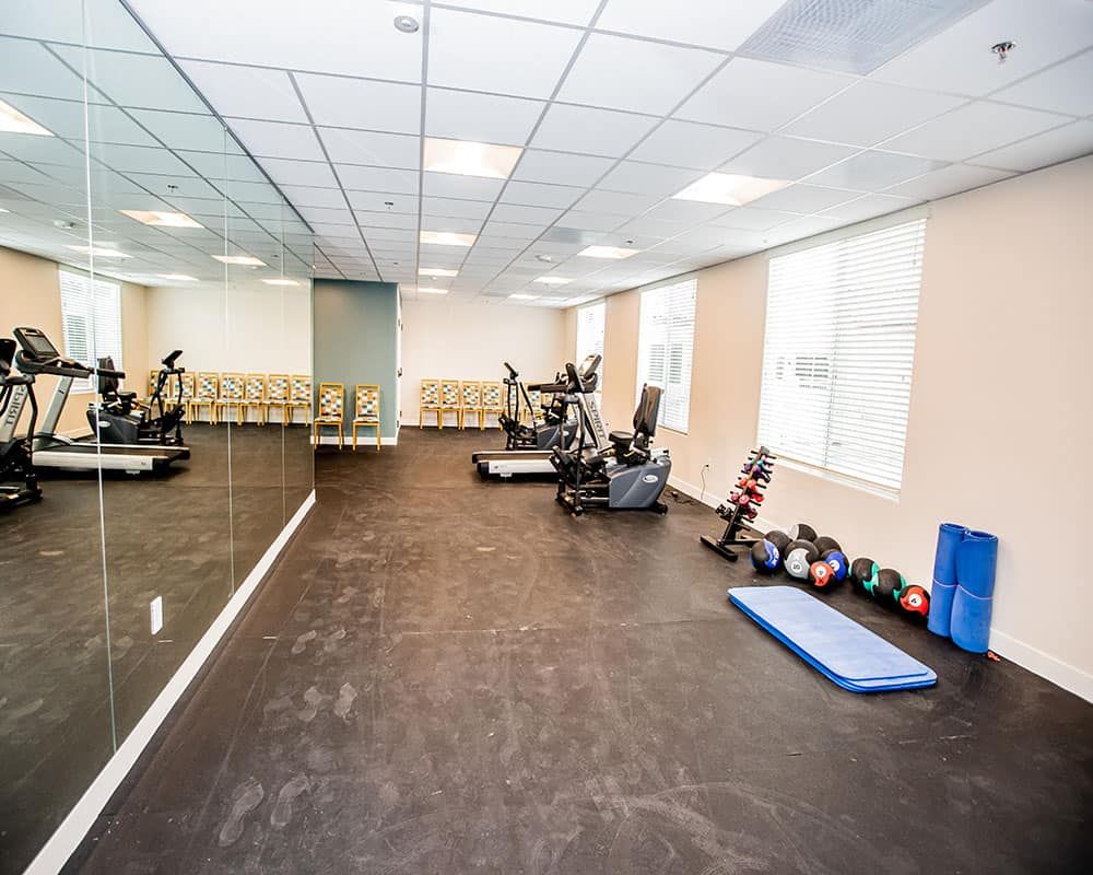 A modern gym with exercise equipment including treadmills, dumbbells, and exercise mats.