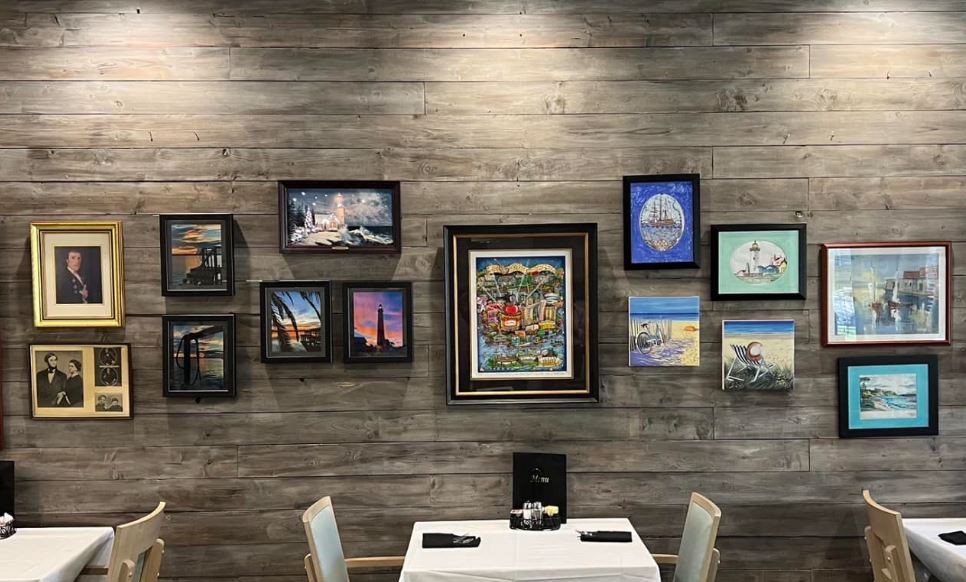 A cozy dining area adorned with a variety of framed paintings on the wall.