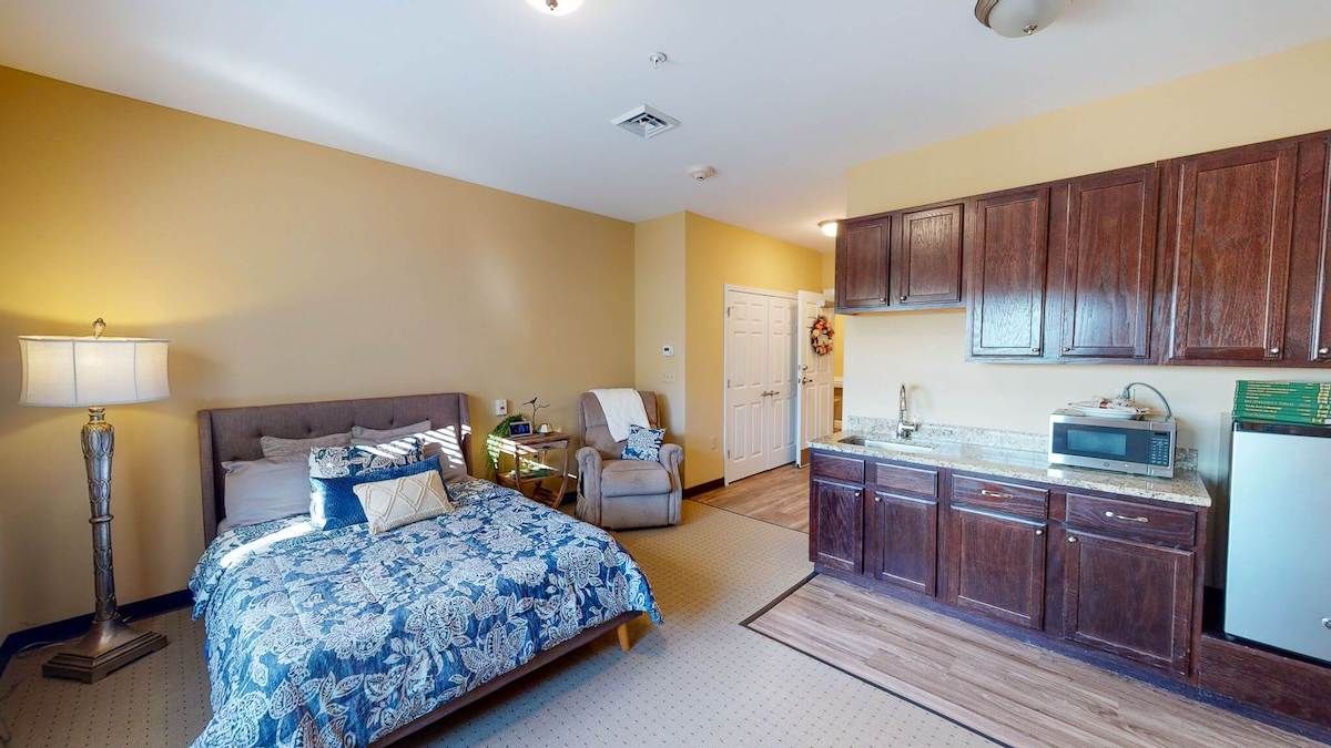 A cozy studio apartment with a neatly arranged bedroom and kitchenette.