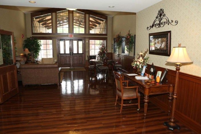 A welcoming reception area featuring elegant wooden flooring, stylish furniture, and ample natural light from large windows.