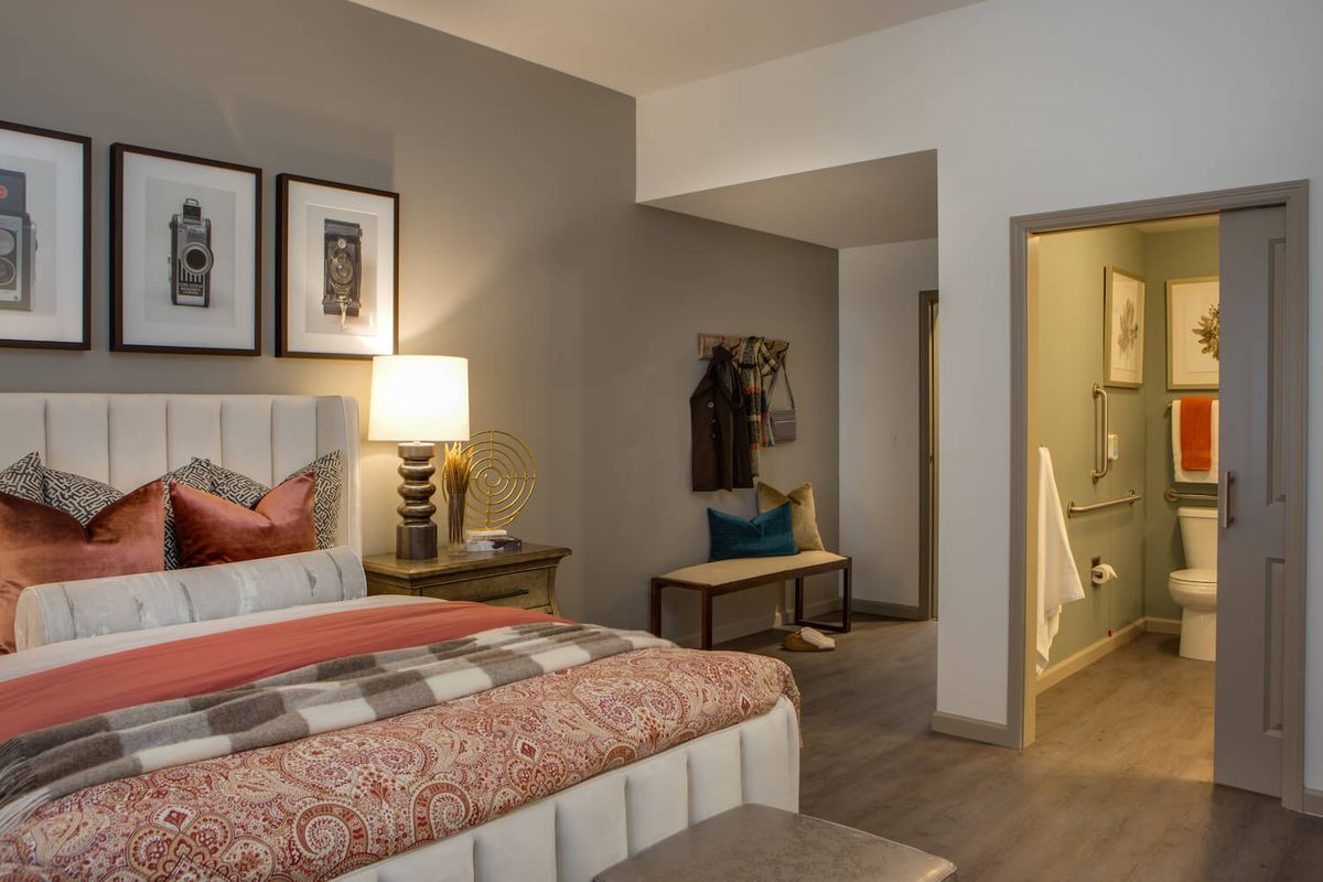 A cozy hotel room with modern decor, featuring a comfortable bed, artwork on the walls, and warm lighting.