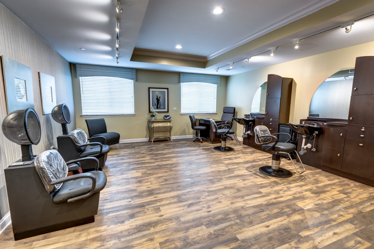 A modern barber shop with stylish chairs and mirrors, featuring warm lighting and wooden flooring.