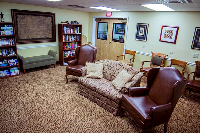A cozy waiting room with various seating options and a bookshelf.