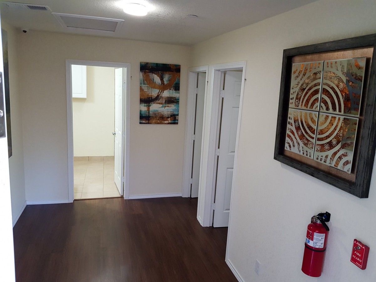An interior hallway with artwork on the walls and doors leading to other rooms.