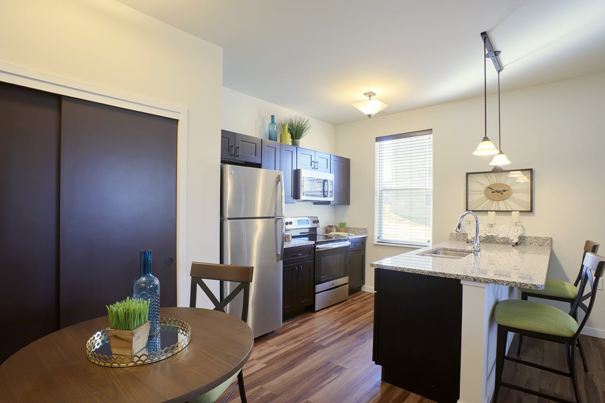 A modern kitchen with stainless steel appliances and a small dining area.