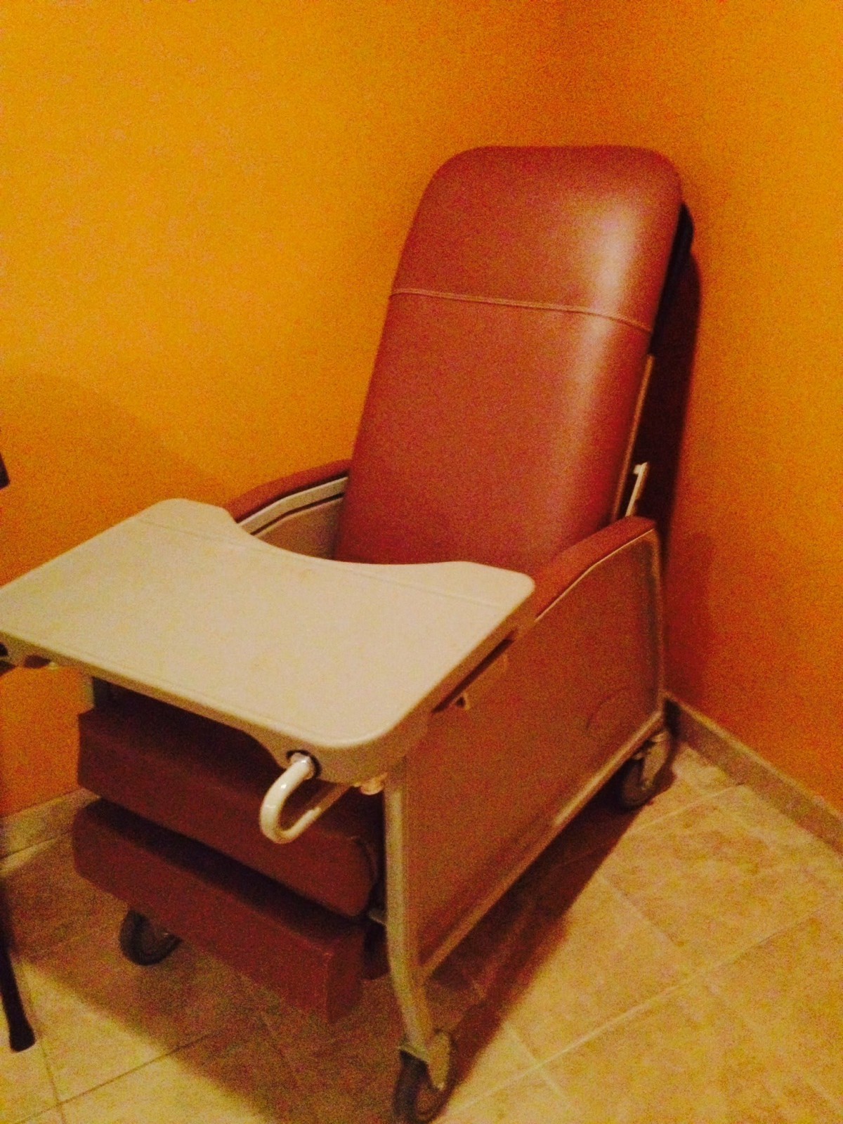 A recliner chair with an attached tray in a room with orange walls.