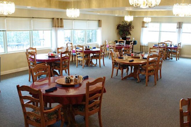 An empty dining area with wooden tables and chairs arranged neatly under soft lighting.