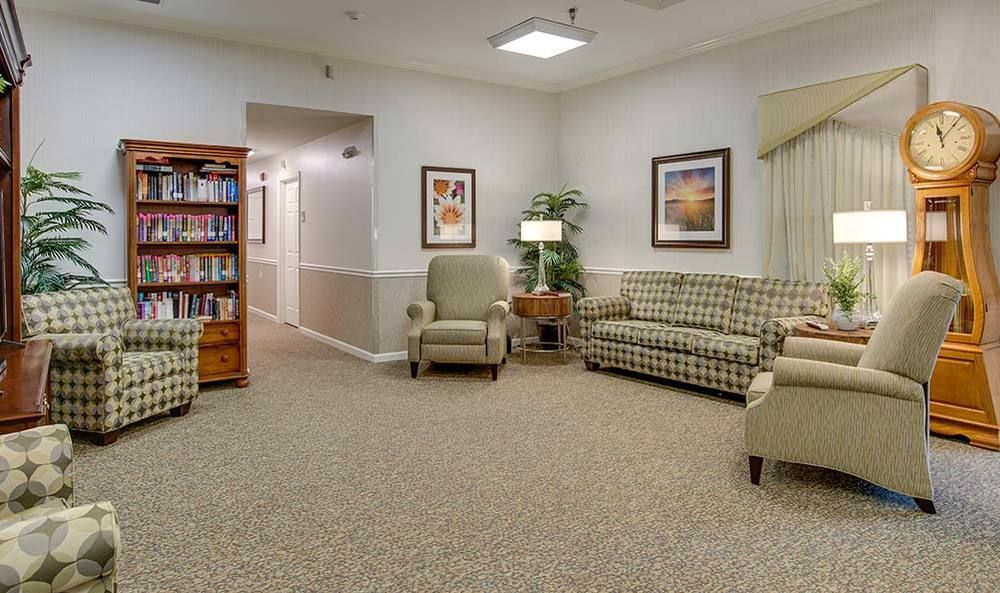A comfortable waiting room with chairs, a sofa, and a bookshelf.