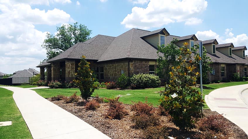 A suburban brick house with a well-maintained garden and landscaped yard.