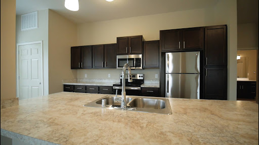 A modern kitchen featuring dark cabinets, stainless steel appliances, and a spacious countertop.