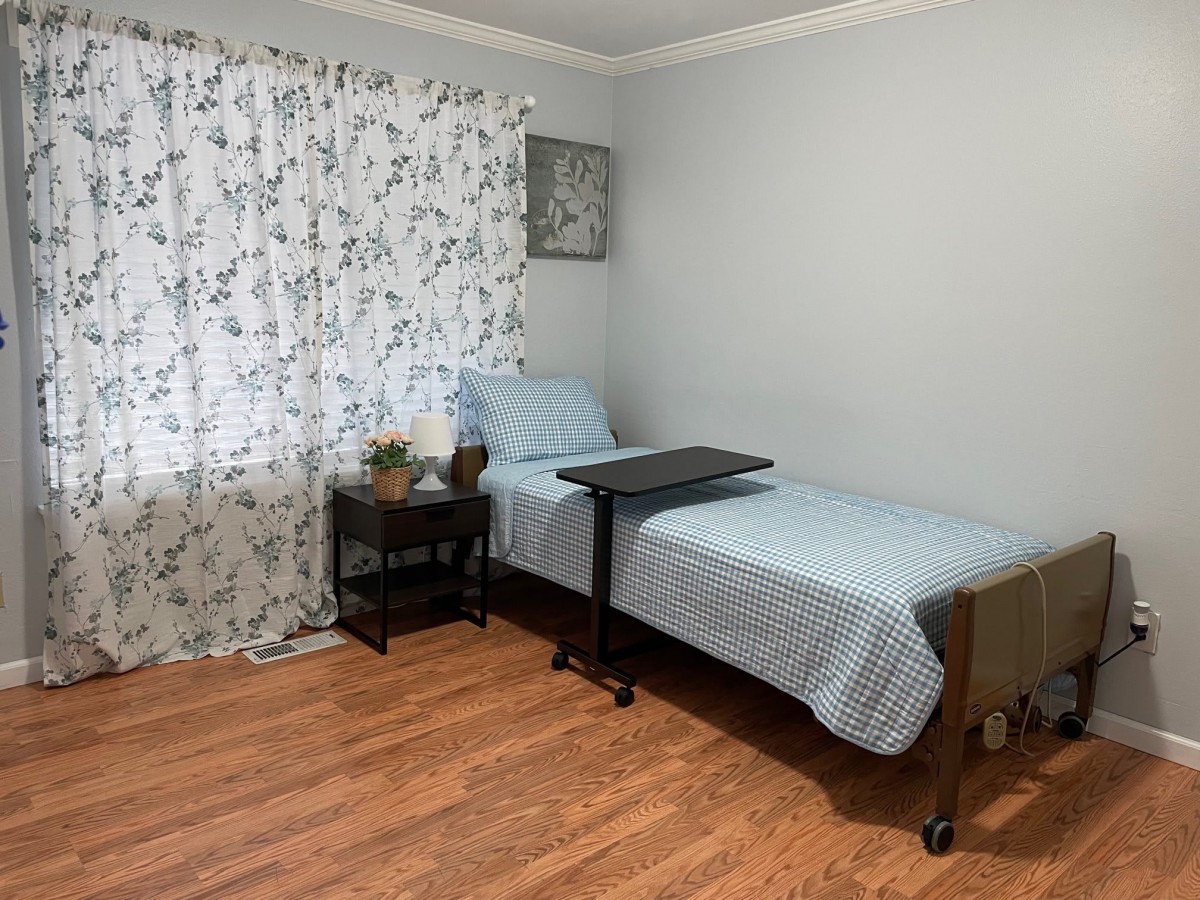 A cozy bedroom with a single bed, nightstand, and floral curtains.