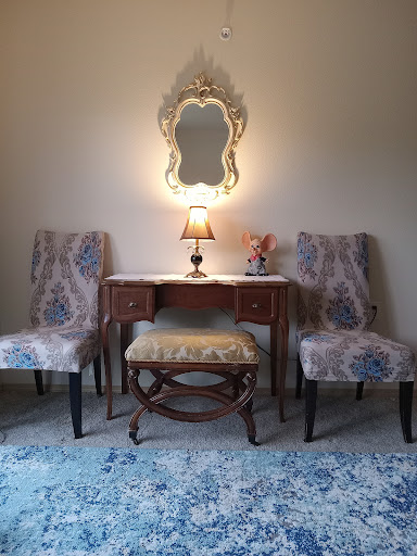 A charming vanity setup featuring a decorative mirror, elegant chairs, and a soft lamp, creating a cozy corner.