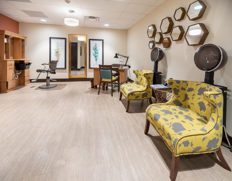 A modern salon interior featuring stylish chairs, decorative mirrors, and framed artwork.