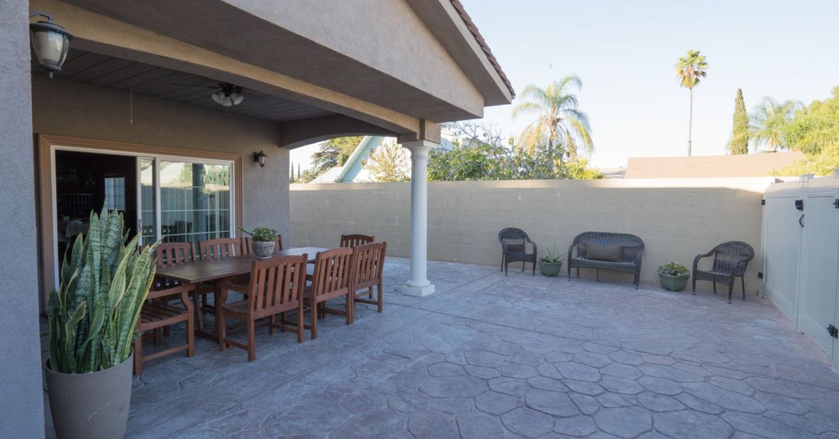 A spacious backyard patio with a dining set and additional seating.