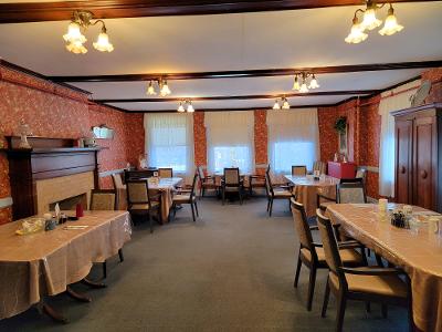A cozy restaurant interior featuring neatly arranged tables and chairs, with soft lighting and brick walls.