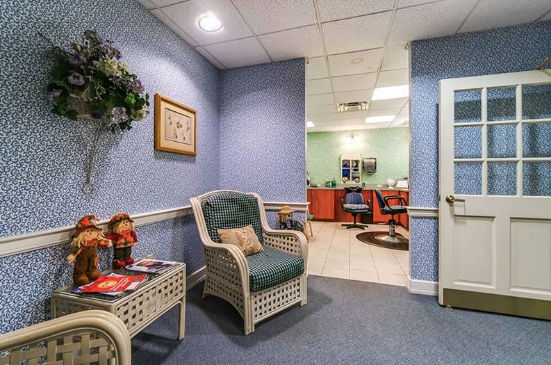 A cozy waiting area with wicker furniture leading into a salon room.