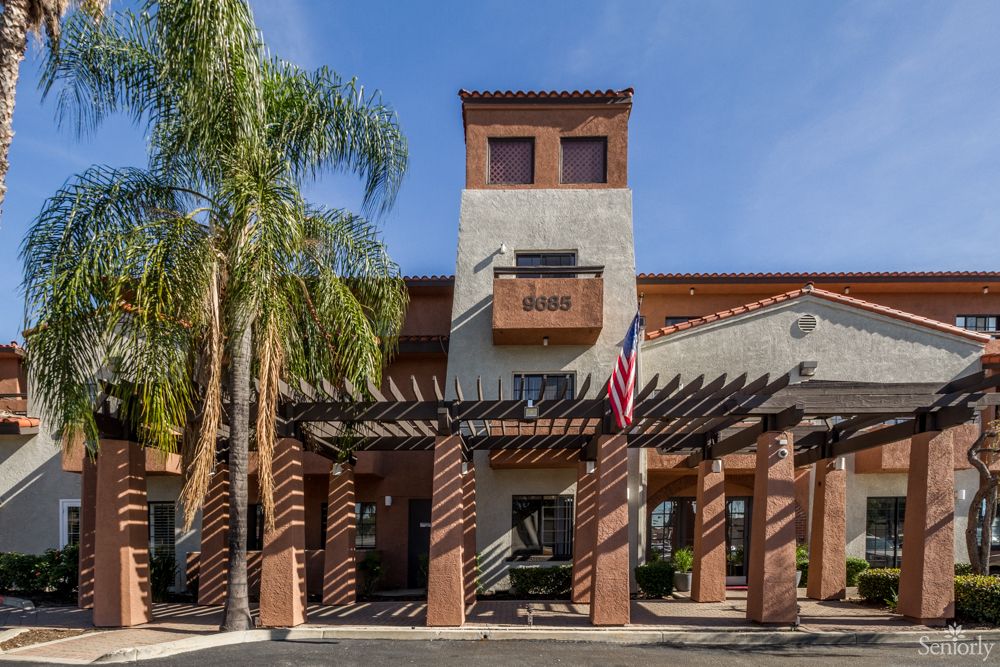 A hotel exterior with palm trees and an entrance under a sunny sky.