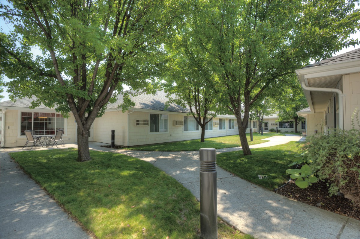 A serene residential area with houses surrounded by trees and well-maintained pathways.