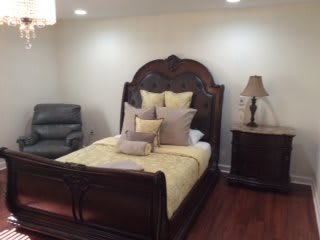 A cozy bedroom with a wooden bed frame, plush pillows, and matching nightstand.