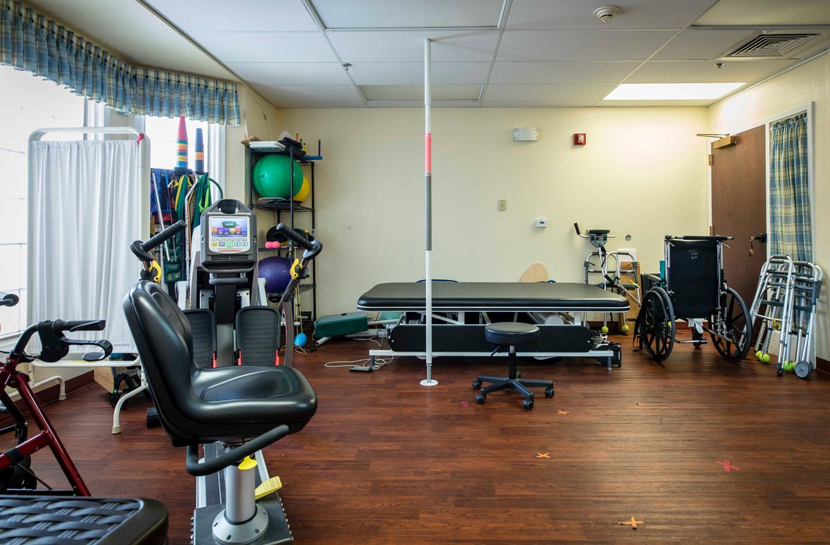 A physical therapy room equipped with exercise machines and a therapy bed.