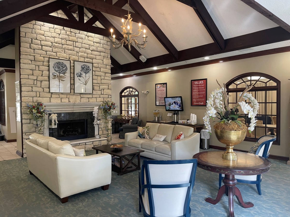 A cozy living room with a stone fireplace, elegant chandelier, and comfortable seating.