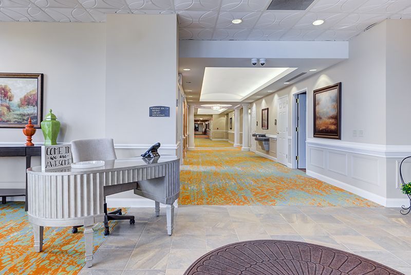 A spacious lobby area with a desk, artwork, and carpeted hallway.