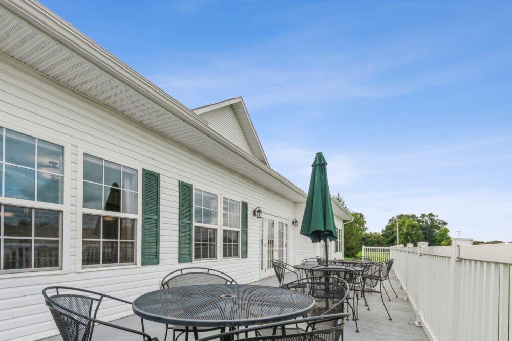 An outdoor patio area with tables, chairs, and umbrellas next to a building.