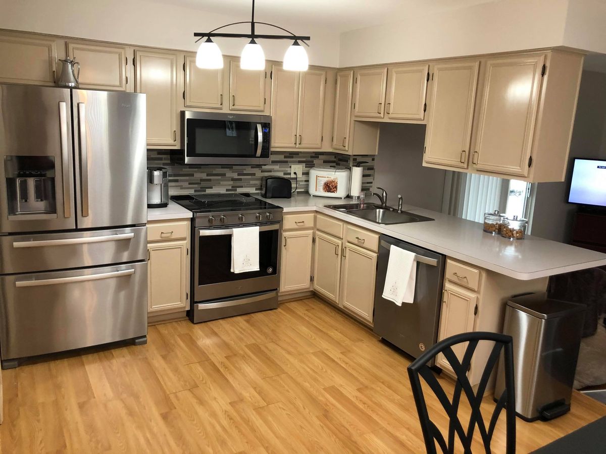 A modern kitchen with stainless steel appliances and wood flooring.