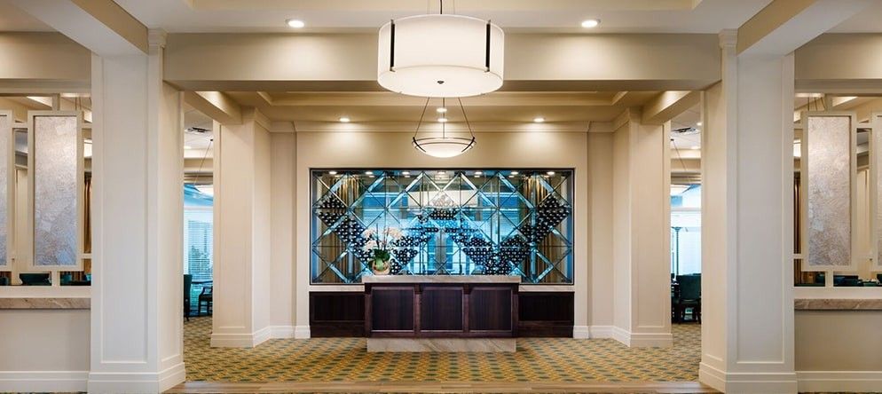Elegant hotel lobby with a central wine rack and chandelier.