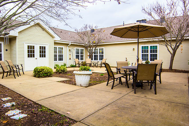 A cozy backyard patio with seating and an umbrella, adjacent to a house.