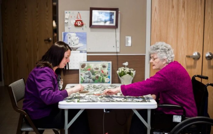 Two people sitting at a table working on a puzzle together.