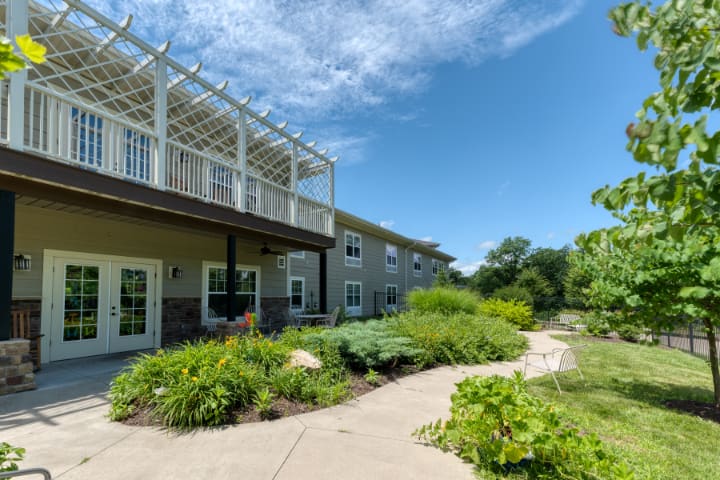A modern building with a garden pathway and lush greenery under a clear blue sky.