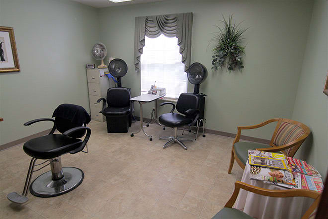 A cozy salon interior featuring styling chairs, hair dryers, and a small waiting area.