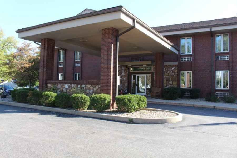 A hotel entrance with a covered driveway and surrounding greenery.