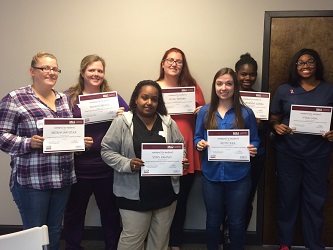 A group of individuals proudly displaying their certificates in a celebratory moment.