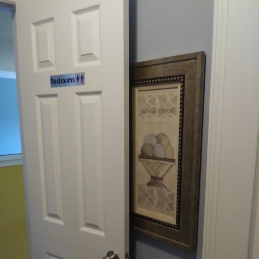 A bathroom door partially open, revealing framed artwork on the wall.