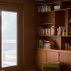 A cozy room with a wooden bookshelf filled with books.