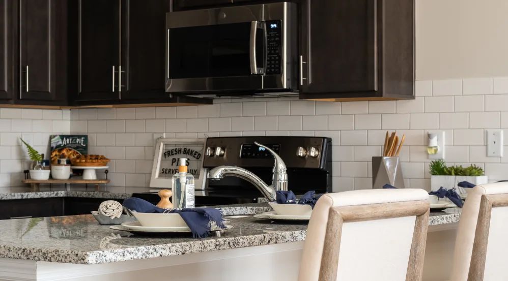 A modern kitchen with a countertop featuring a sink, dishes, and dark cabinetry.