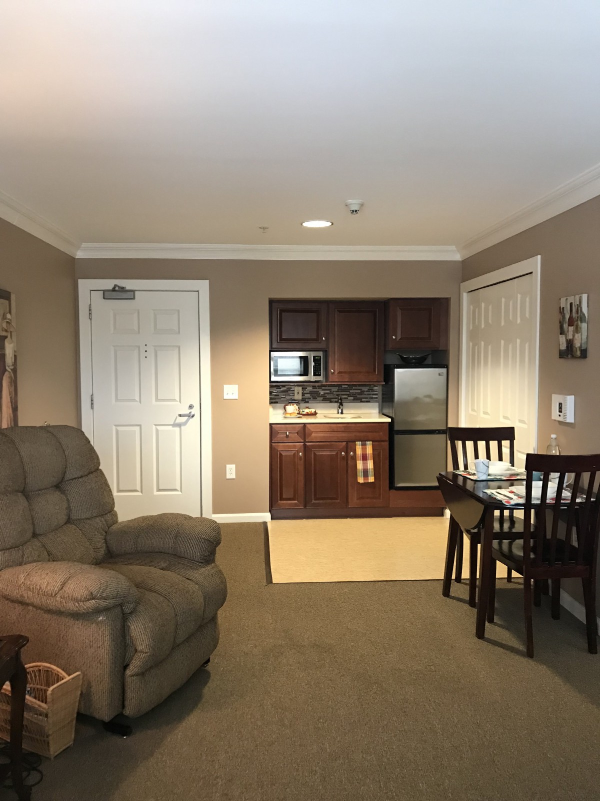 Cozy living room with armchair, dining area, and kitchenette.