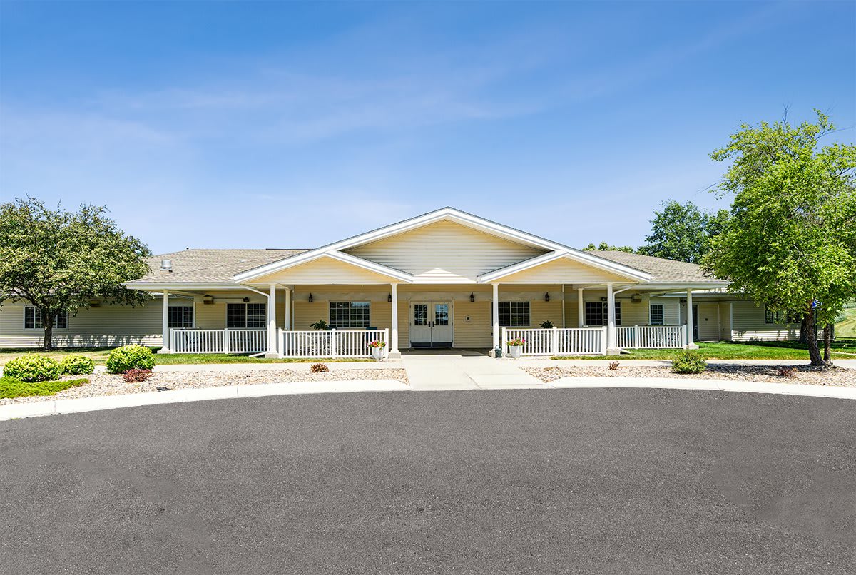 A spacious residential building with a large driveway and covered porches.