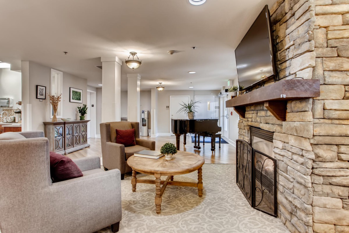 A cozy living room with modern decor, featuring a fireplace, television, and a grand piano.